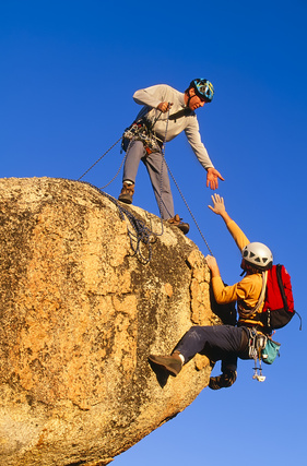 Team of climbers reaching the summit of a rock pinnacle.